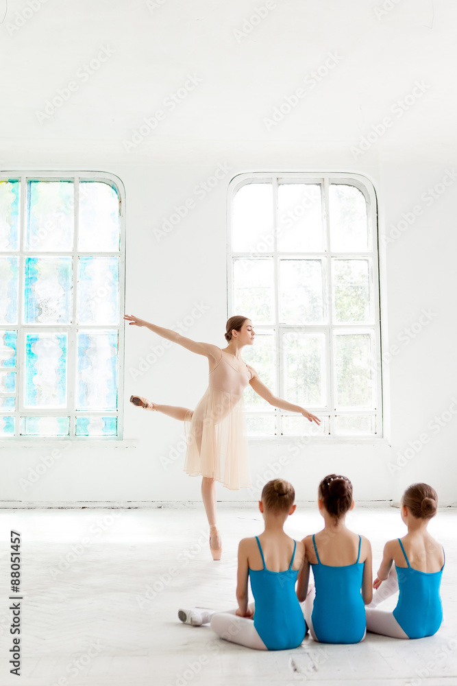 Obraz premium Three little ballerinas dancing with personal ballet teacher in