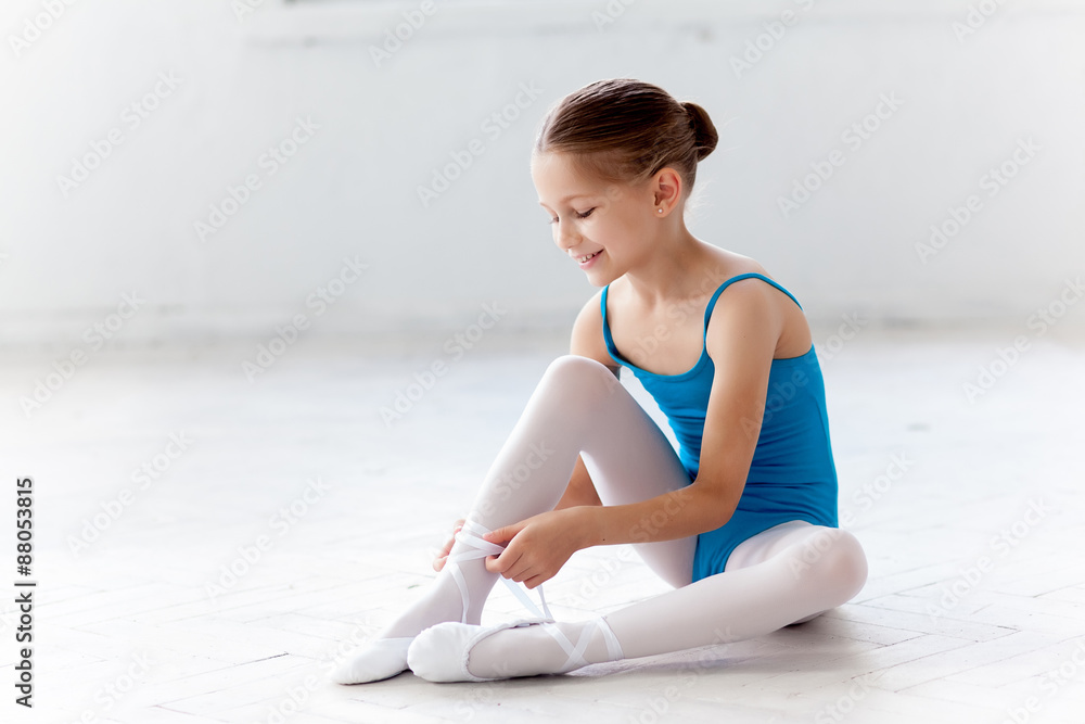Fototapeta premium Beautiful little ballerina in blue dress for dancing puting on
