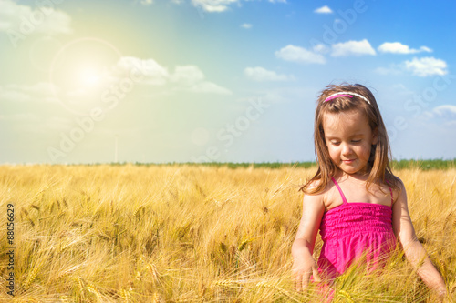 Little girl having fin in the wheat field on a sunny day.
