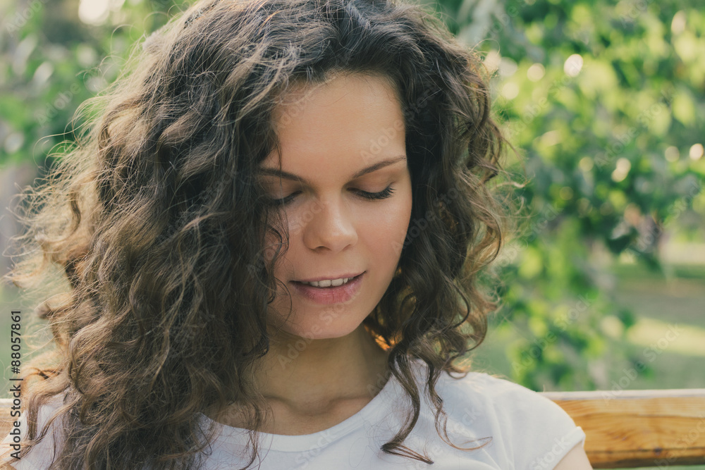 Portrait of a young attractive girl with curly hair on a bench i Portrait of a young attractive girl with curly hair on a bench i