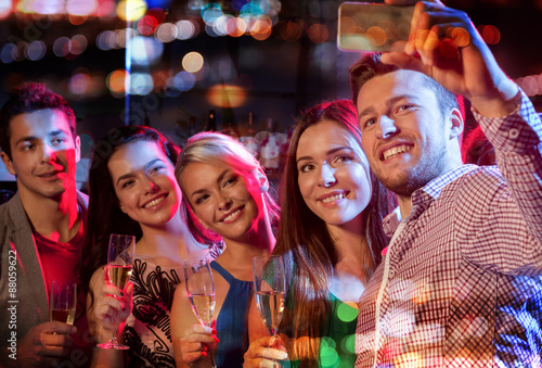 friends taking selfie by smartphone in night club