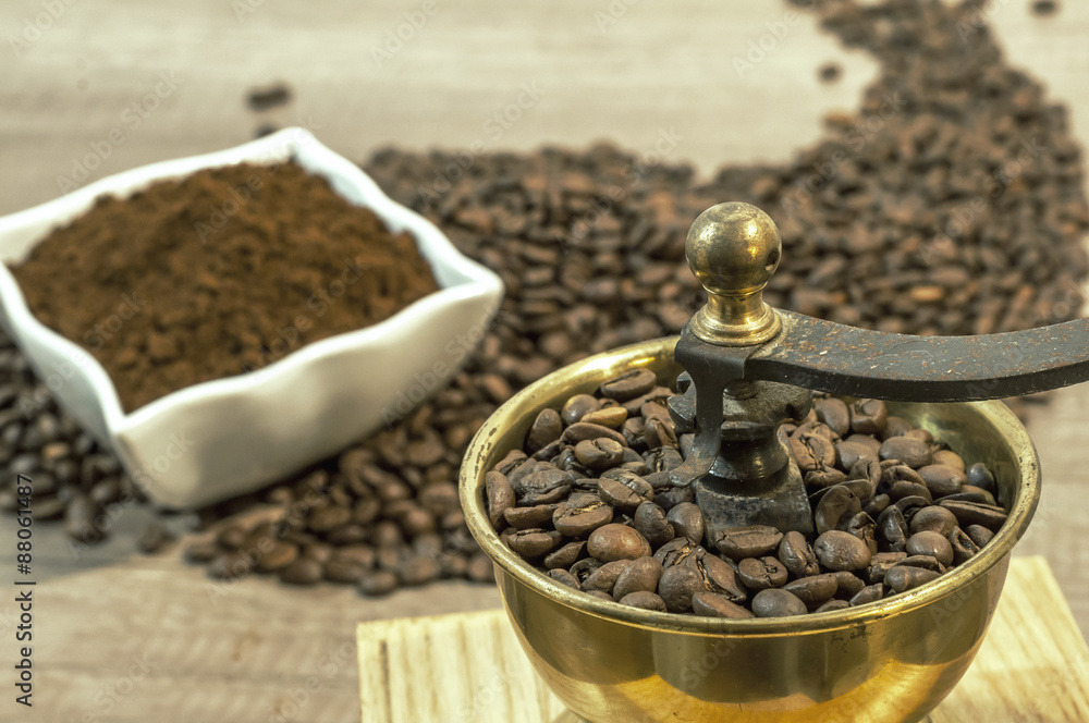 Coffee grinder with coffee beans and ground coffee in bowl on wo