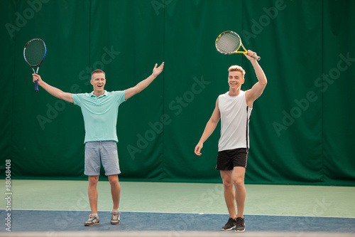 Mixed doubles player hitting tennis ball with partner 
