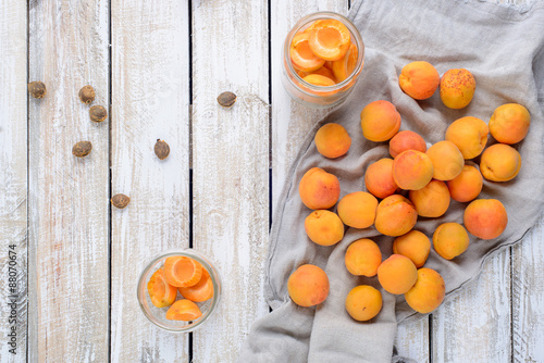 Homemade conserve of apricot pieces in glass jars/Slices of fresh apricot in glass jars and napkin on a wooden table