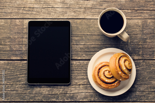 cinnamon rolls, cup of coffee and computer tablet