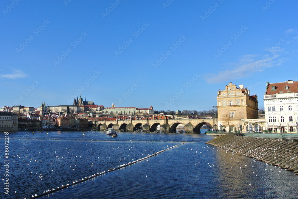 Charles' bridge and Vltava river in Prague, Czech Republic, with Hradcany castle in the background, on a sunny day.