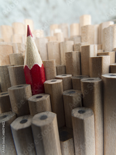 Close-up of identical graphite pencils and one red leading crayon