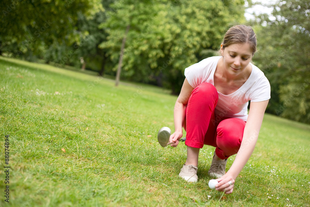 young woman placing a golf ball on a tee. young woman placing a golf ball on a tee.