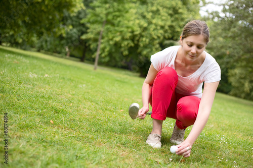 young woman placing a golf ball on a tee.