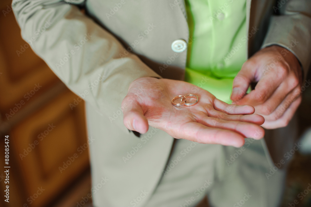 Groom holding wedding rings in his hands