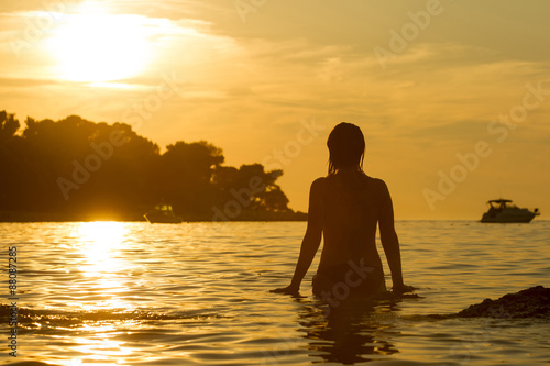 Woman standing in shallow at sunset