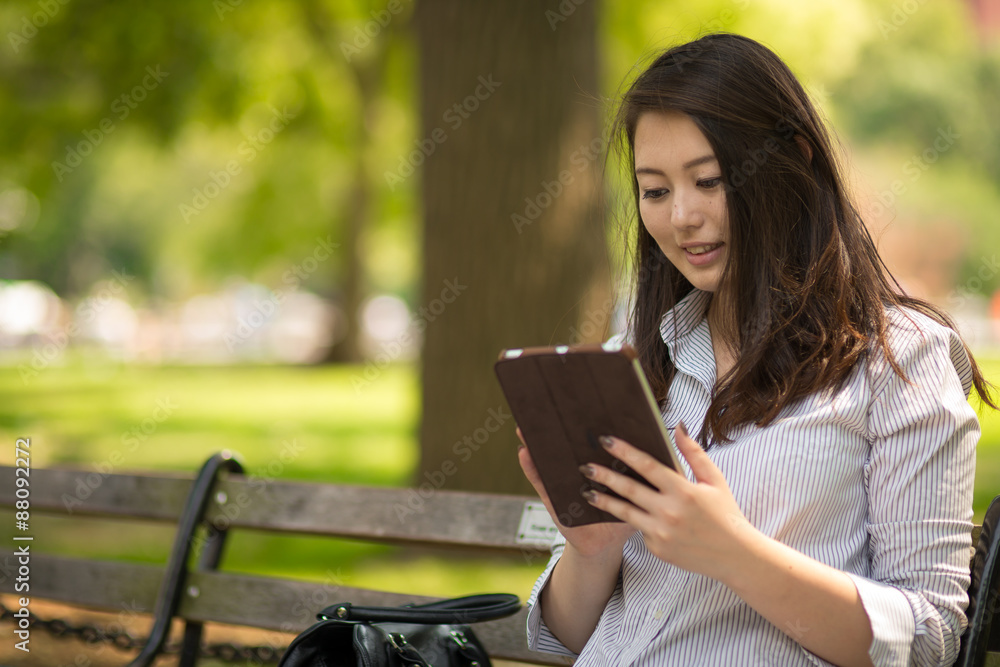 Obraz premium Young Asian woman in city using tablet computer