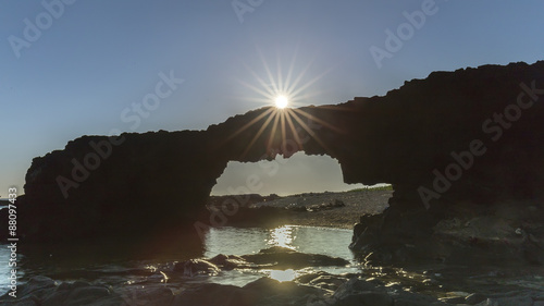 Sunrise atop the stone arch gate with bolt Sunstar Ly Son Island on rolling stone gate gives the feeling of the sun was playing. photo