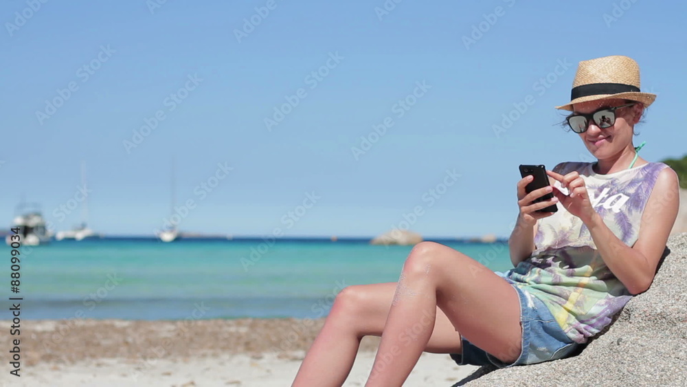 Young woman reading or writing sms on her mobile smartphone by turquoise sea Young woman reading or writing sms on her mobile smartphone by turquoise sea