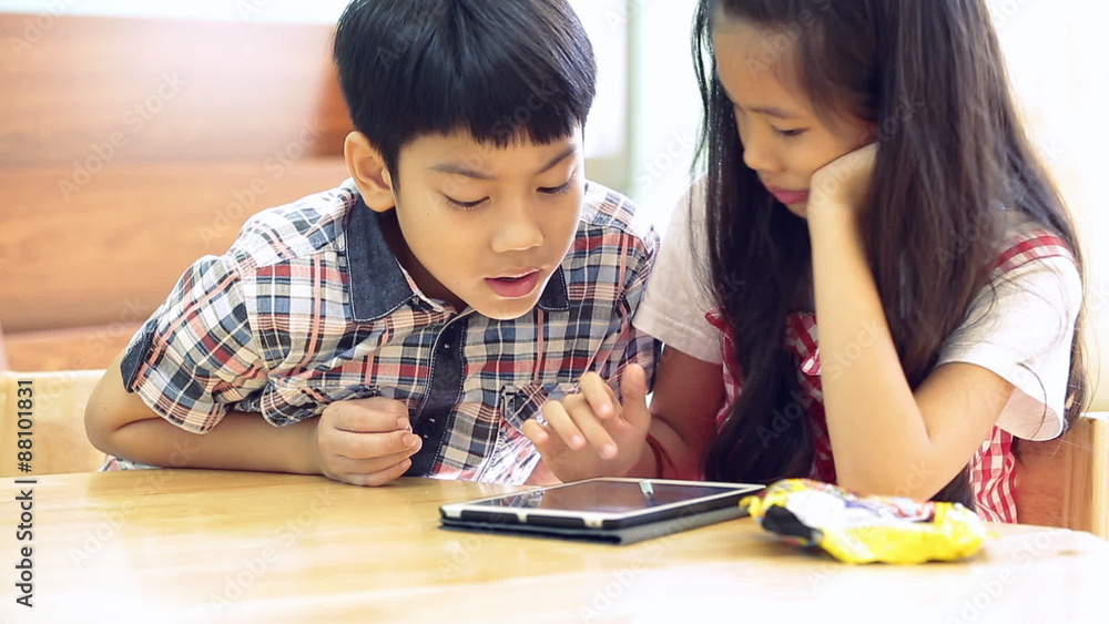 Asian children using a digital tablet together . Asian children using a digital tablet together .
