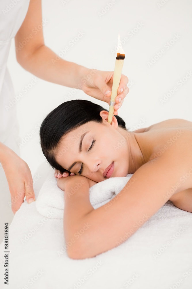 Beautiful woman receiving ear candle treatment at spa center Beautiful woman receiving ear candle treatment at spa center