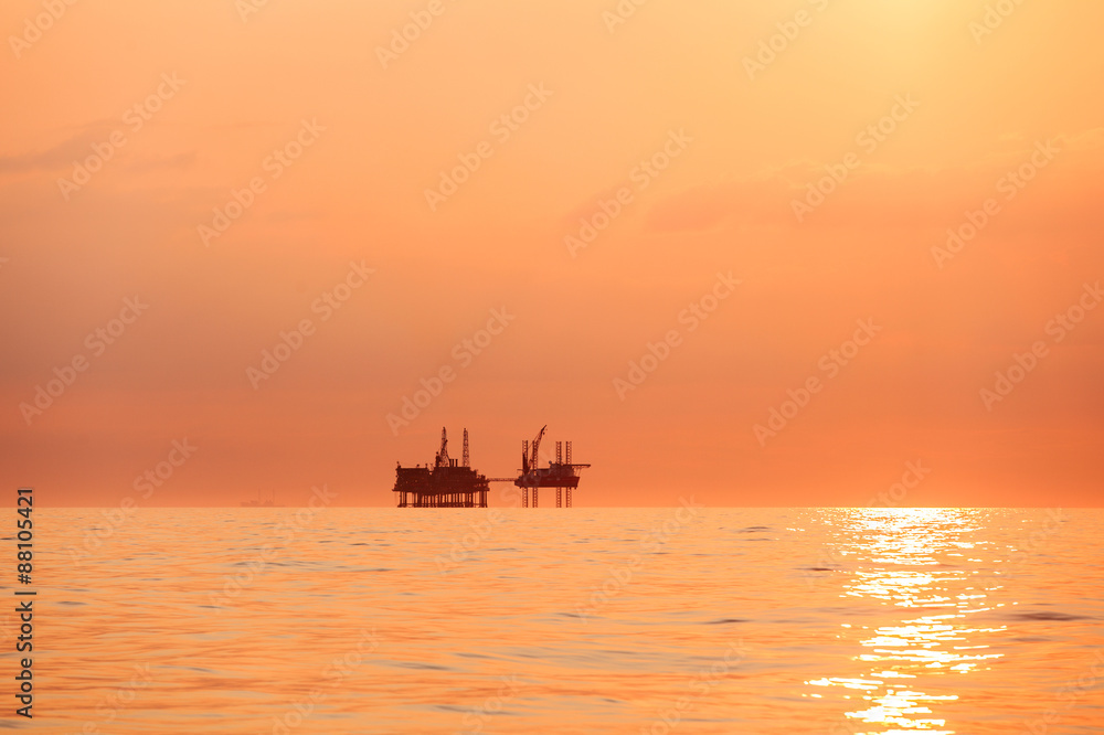 Silhouette of oil platform at sunset