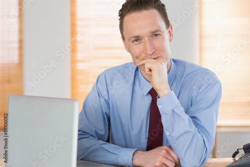 Happy businessman sitting at his desk