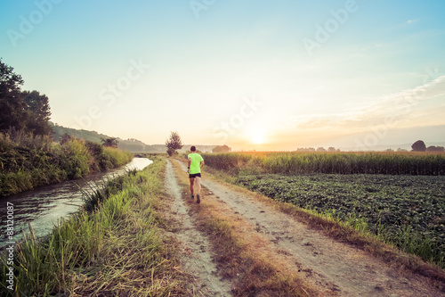 Ragazzo che corre all'alba su strada di campagna in estate