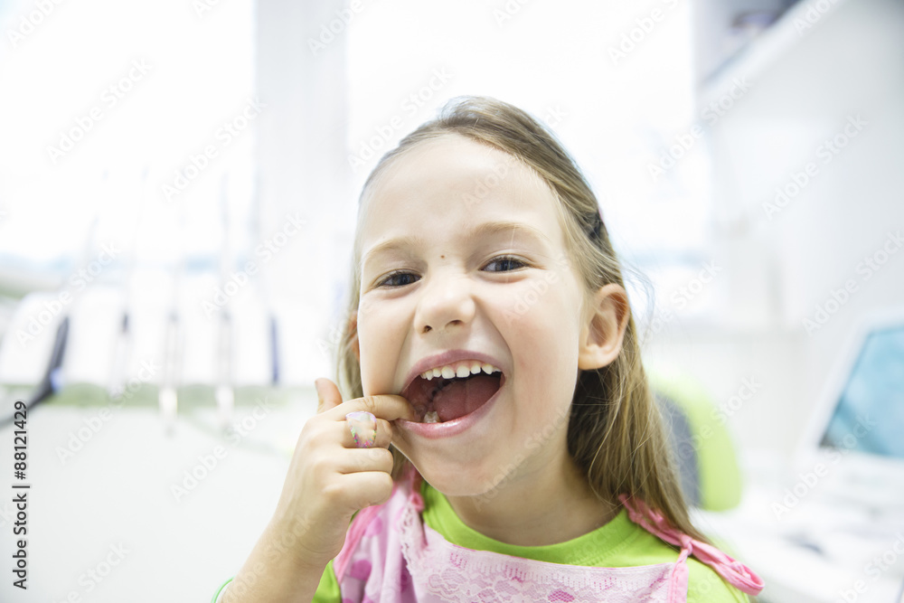 Girl showing her healthy milk teeth at dental office