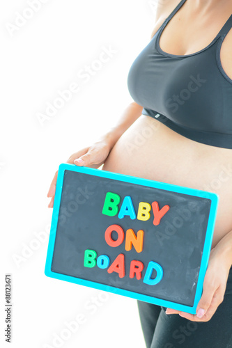 Pregnant woman holds a baby on board colored text on blackboard over her belly
