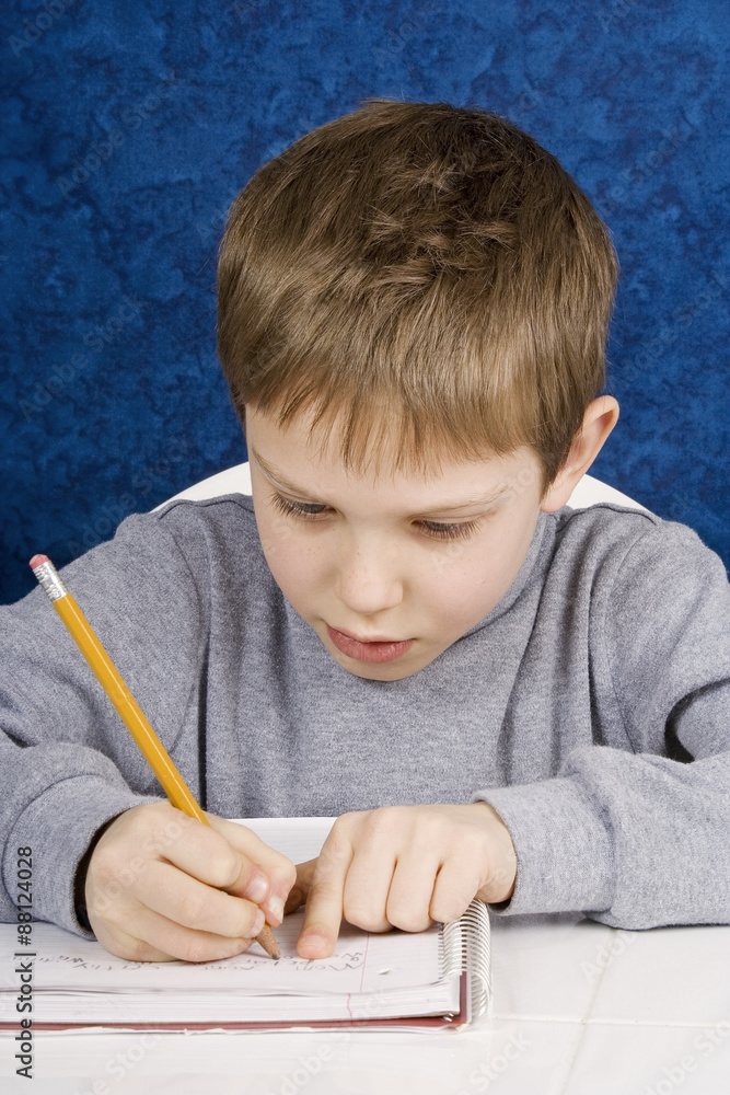 Young Boy Practices Writing – A young box writes on notebook paper, practicing his writing. Young Boy Practices Writing – A young box writes on notebook paper, practicing his writing.