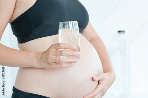 Canvas-taulu Healthy mother to be holding a glass of water in front of her belly