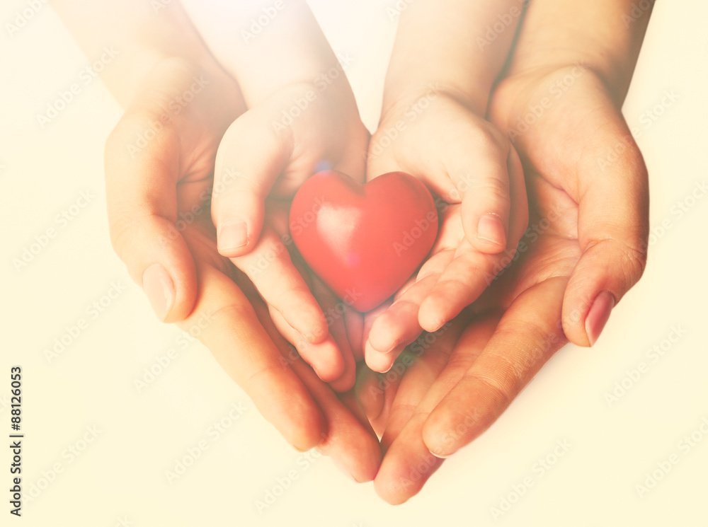 Heart in child and mother hands on light background Heart in child and mother hands on light background
