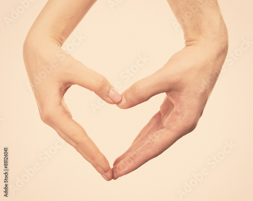 Heart shaped by male and female hands on light background