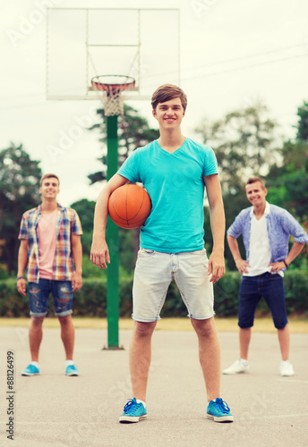 group of smiling teenagers playing basketball