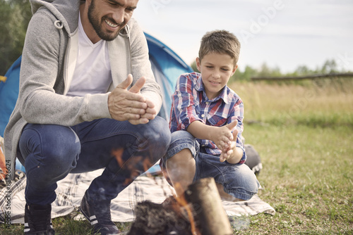 Father and son rubbing hands over the campfire