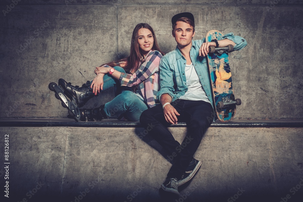 Young couple with skateboard  and rollerblades outdoors