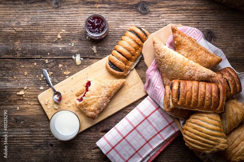 assorted breakfast pastries with jam and milk