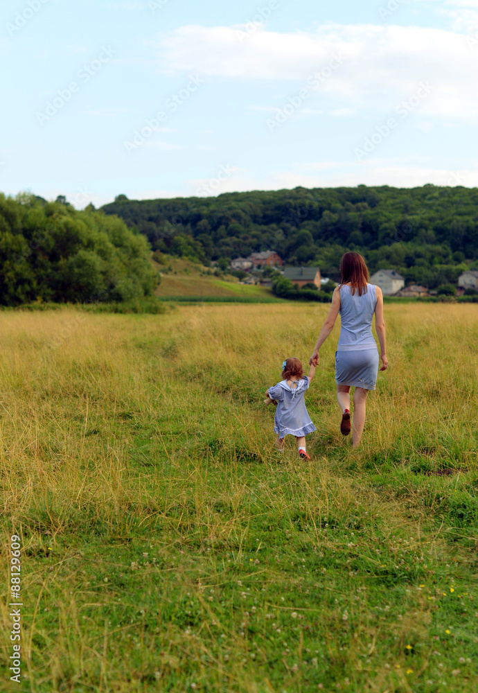 Mother and daughter walking on a pasture