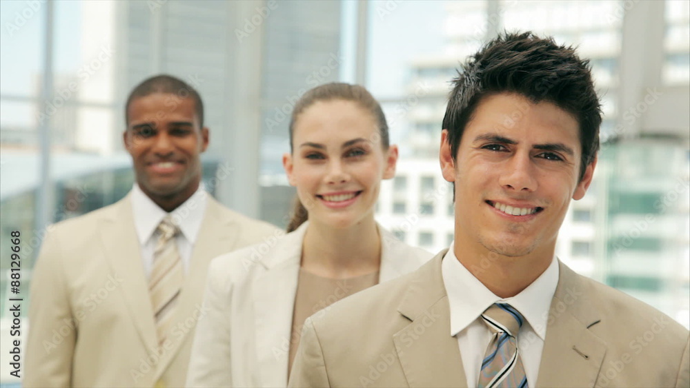 Panning shot of young businessman smiling with coworkers. Young business people are in formals. Multi-ethnic male and female professionals are in brightly lit office. Panning shot of young businessman smiling with coworkers. Young business people are in formals. Multi-ethnic male and female professionals are in brightly lit office.