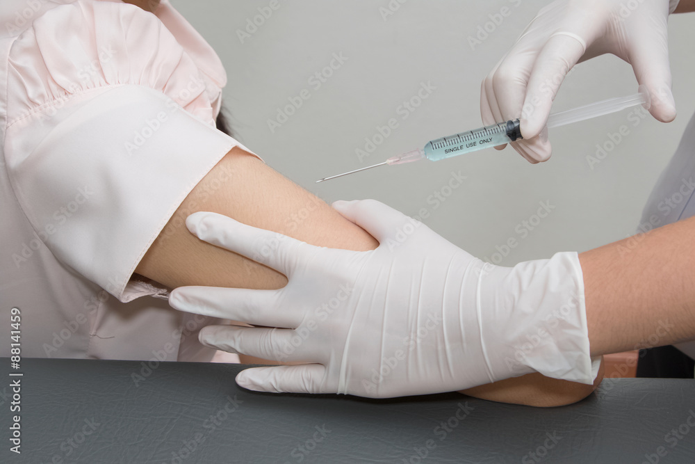 Woman is getting injection with a syringe at hospital Woman is getting injection with a syringe at hospital