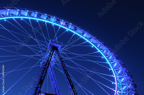 Ferris wheel with blue and light blue illumination against night sky