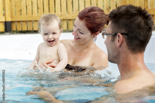 Portrait of young family with baby and toddler in swimming pool