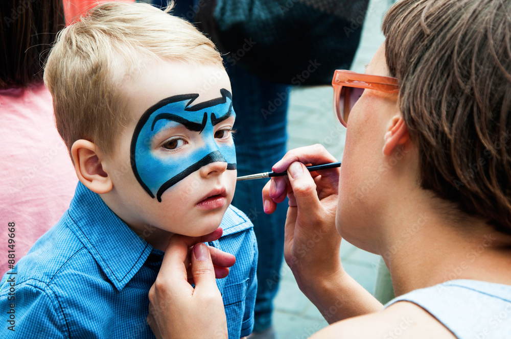 Woman painting face of kid outdoors - obrazy, fototapety, plakaty 