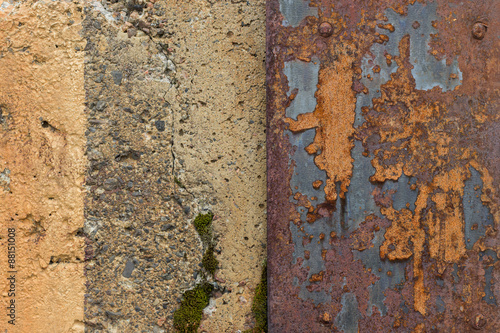 Close-up of weathered concrete wall and a ragged and rusty sheet metal plate.