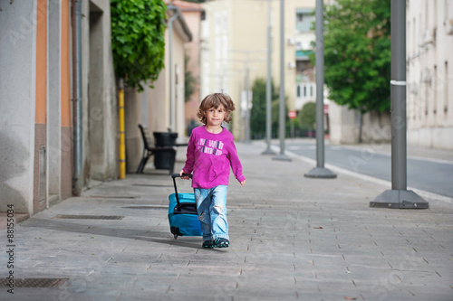 Fotografija Cutle little boy with a luggage bag on the street