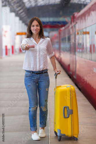 Young caucasian girl with luggage at station traveling by train photo