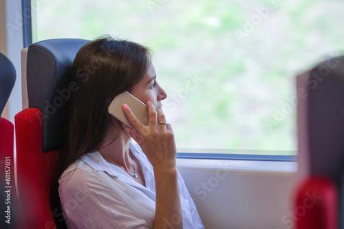 Young businesswoman talking on the phone traveling by train