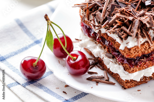 Black Forest cake piece on white plate with cherries berries close-up 