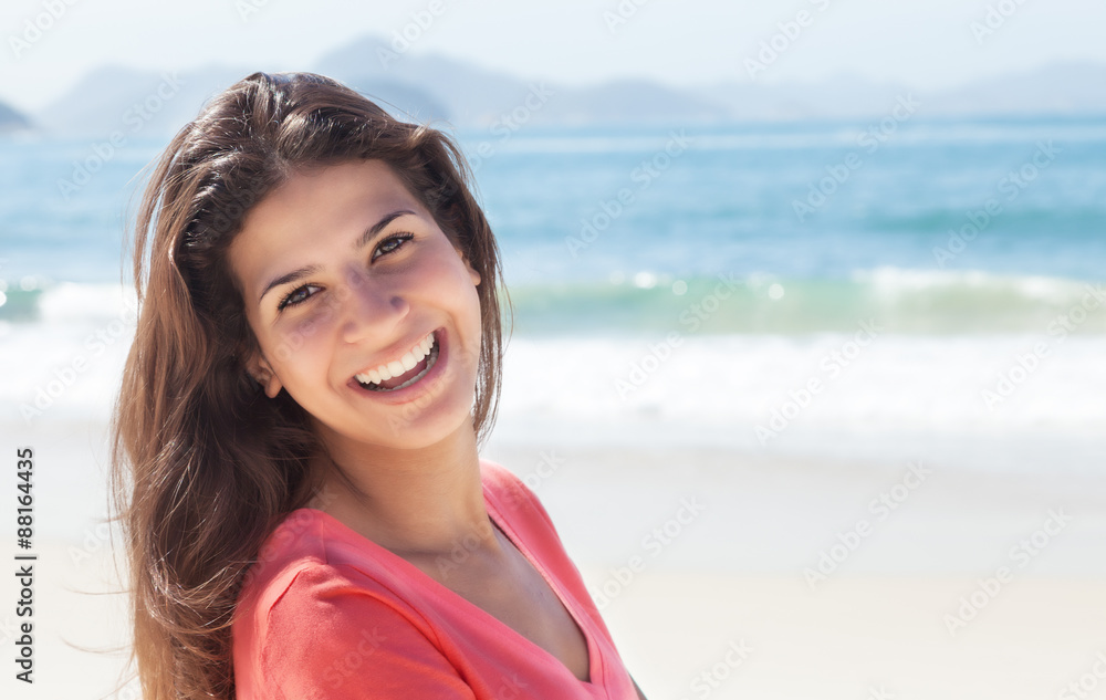 Lachende Frau mit braunen Haaren am Strand