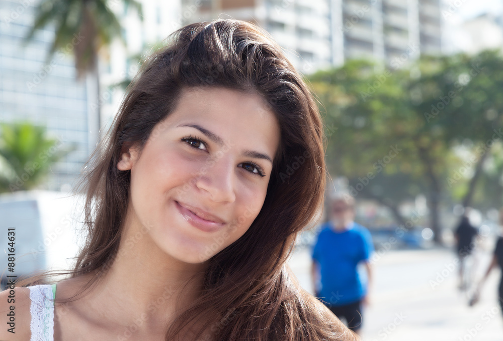 Junge Frau mit braunen Haaren in der Stadt lächelt sanft