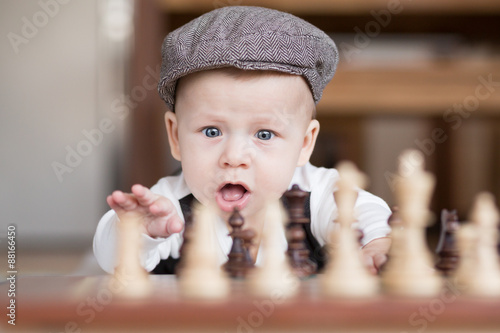 Funny baby playing chess lying on the floor.
