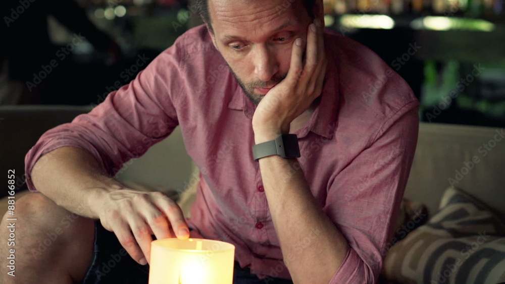 Sad young man sitting by the candle in cafe
Sad young man sitting by the candle in cafe