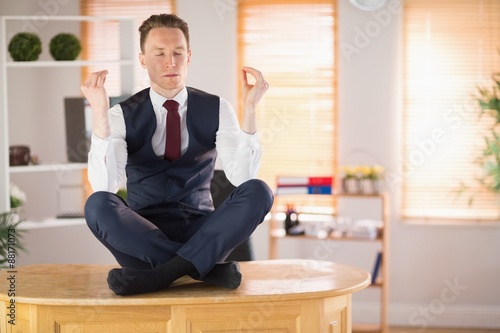 Calm businessman meditating in lotus pose