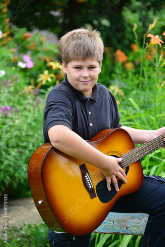 Teen boy playing guitar outdoor in a summer